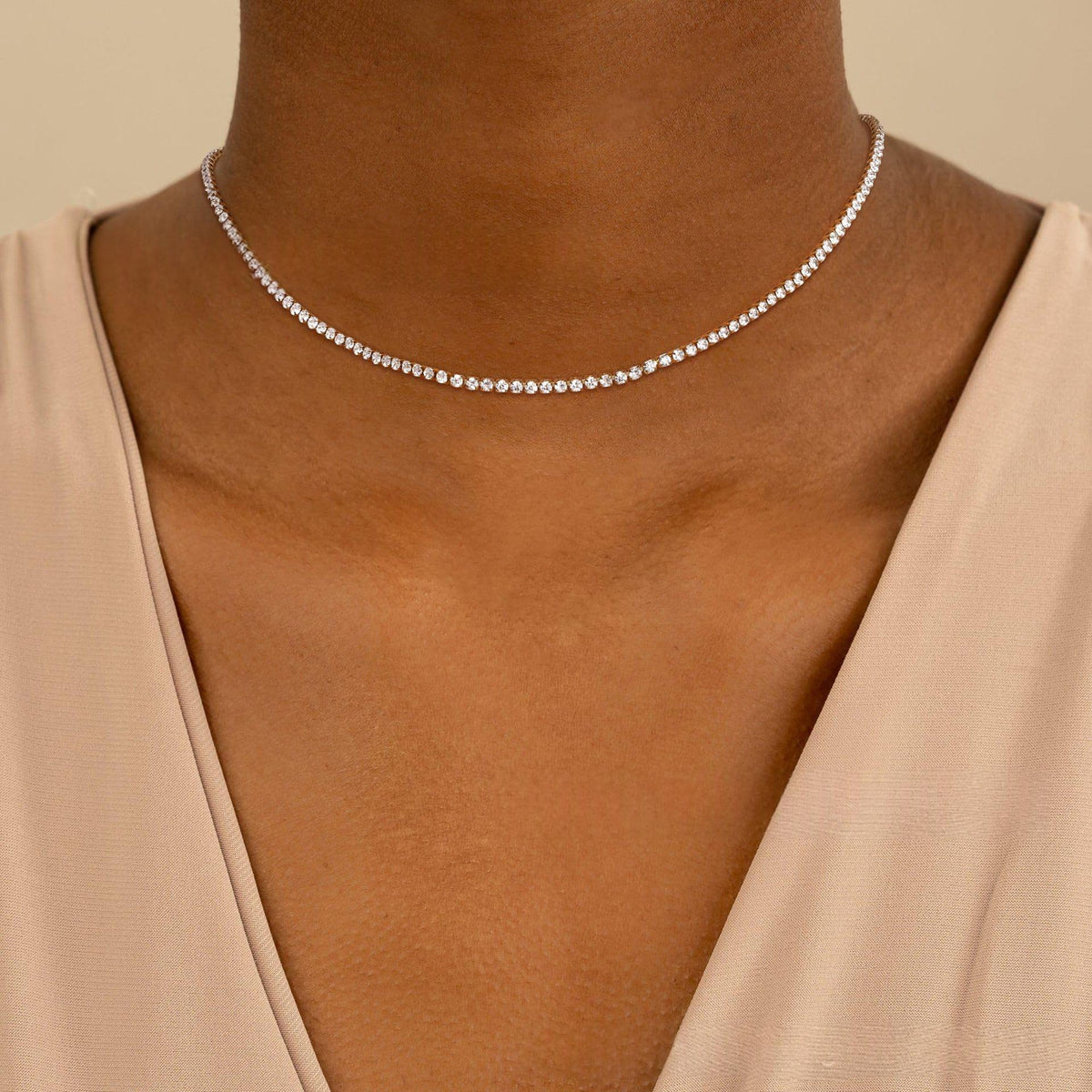 Collier tennis zircons argenté porté au cou avec une robe beige